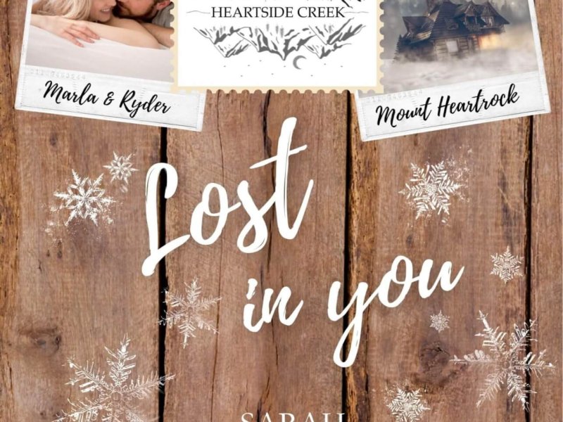 Buchcover Roman Heartside Creek – Lost in you (Cosy New Adult Winter Romance): Hintergrund in Holzoptik mit angedeutetem stilisiertem Gebirge und der Silhouette einer Hütte im unteren Randbereich. An einer Lichterkette im oberen Bildbereich hängen drei Postkartenfotos. Auf dem ersten ein Paar, die unter einer Bettdecke hervorspitzen, eine blonde junge Frau und ein dunkelblonder junger Mann mit Bartansatz. In der Mitte ein Bild von einem stilisierten Gebirge mit der Bezeichnung Heartside Creek, dem Haupttitel der Buchreihe, und rechts ein Bild einer Nebelumwobenen Berghütte im Schnee. Die Bilder sind mit Holzwäscheklammern aufgehängt.